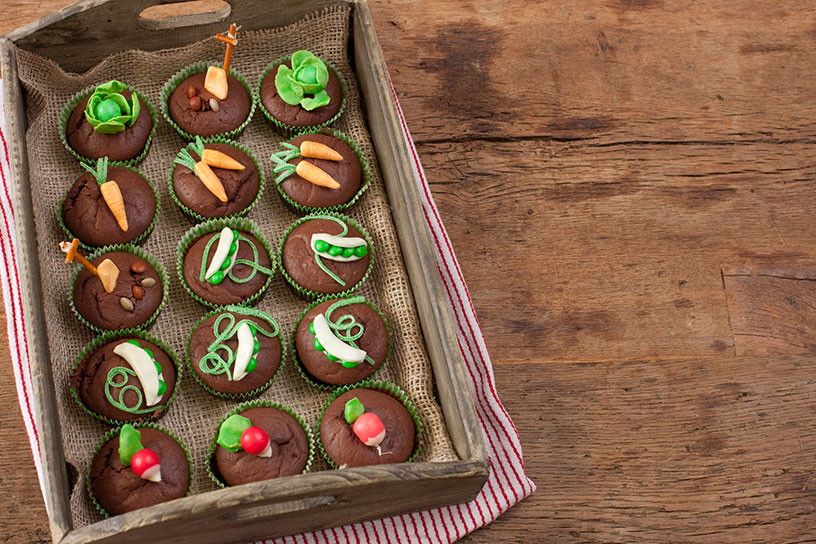 Chocolademuffins bedekt met een oogst van marsepein worteltjes, sla, radijsjes en erwten
